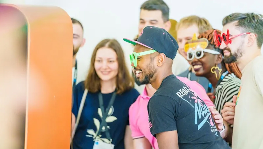 A colorful photo from the JS Heroes conference, showing several smiling attendees wearing novelty glasses